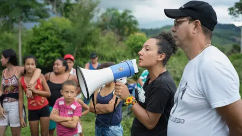 Pablo Cuellar Isabel Zuleta addresses people with a megaphone