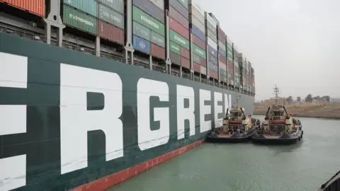 Reuters Tug boats try to move the Ever Given, a container ship blocking the Suez Canal (25 March 2021)