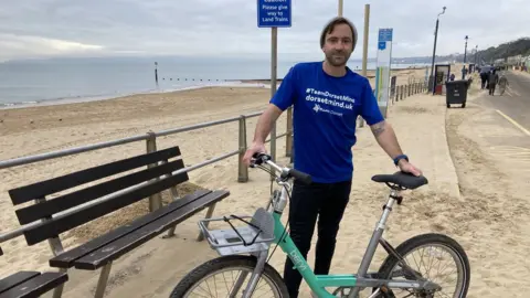 BBC David Haze with bike on sandy beach