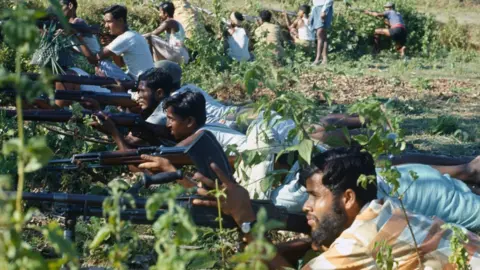 Bettmann/Getty Many Bangladeshi men lined up next to each other, lying on the ground holding rifles