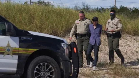 Getty Images A migrant being arrested by Texas police in 2022