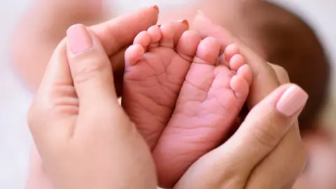Thinkstock Baby's feet being held in adult hands