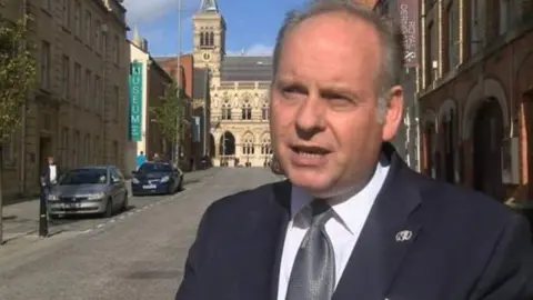 Man with short grey hair wearing a suit and standing in Northampton town centre