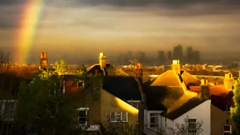 Getty Images Rainbow over the rooftops of London, with Canary Wharf in the distance