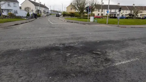 Liam McBurney/PA Wire Scorched section of the Dungiven Road on 4 April where wooden pallets where set alight the night before