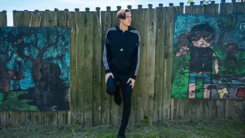 boy standing against fence