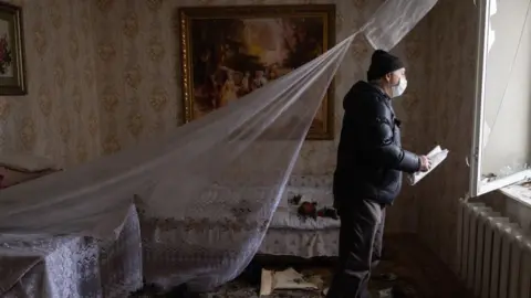 Getty Images Man examines damage to building