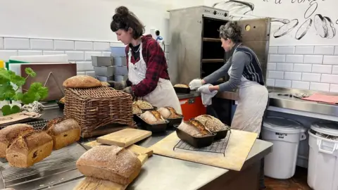 Bakers taking bread out of oven