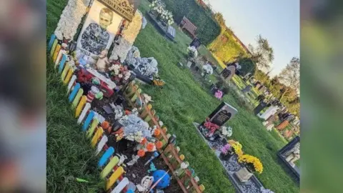 Sharna Andrews Harry-Lee's grave surrounded by low multicoloured picket fence