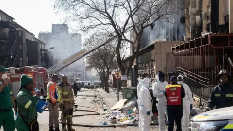 Reuters Members of emergency services work at the scene of a deadly fire which occurred in the early hours of the morning in Johannesburg, South Africa - 31 August 2023