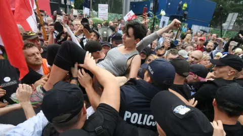 EPA A protester is lifted above the crowd outside the Sejm building in Warsaw, Poland, 20 July 2017