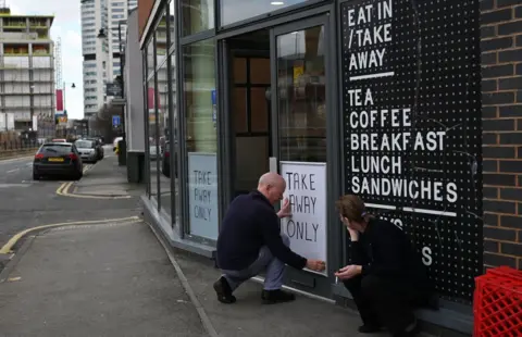 Getty Images A sign saying "Take Away Only" is attached to the window of a cafe in Leeds, northern England on March 21, 2020, a day after the British government said it would help cover the wages of people hit by the coronavirus outbreak as it tightened restrictions to curb the spread of the disease.