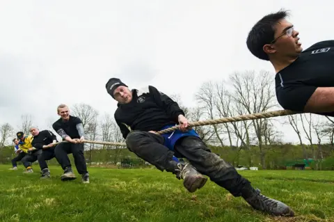 DANIEL STILLER A group of men strain at a tug of war rope.