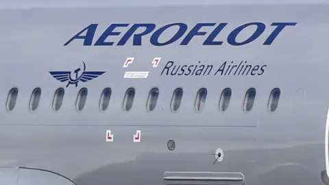 Getty Images The side of a silver plane with the blue logo of "Aeroflot: Russian airlines" in a decal on the side