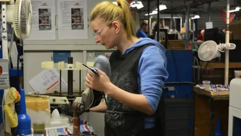 A woman attaches a shoe sole