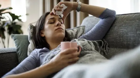 Getty Images sick woman lying on sofa