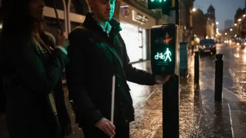 Getty Images Visually impaired man using a cane at a road crossing