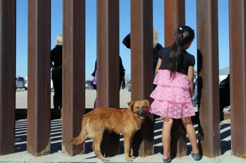 HERIKA MARTINEZ/ AFP/ Getty Images A young girl looks through a fence with her dog.