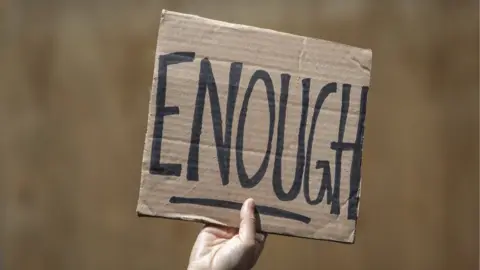 Getty Images A person holds up a sign that reads 'Enough'