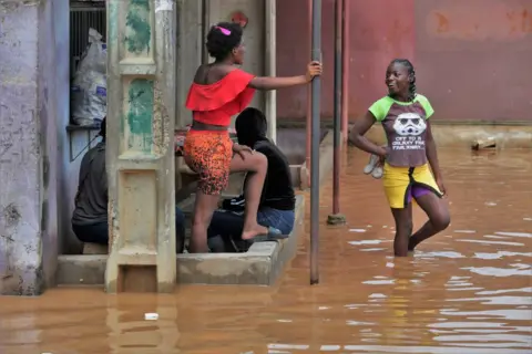 EPA Locals gather next to flooding caused by rain.