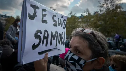 Getty Images A protester wearing a face mask holds a sign in French that reads: 'I am Samuel'