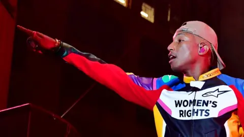 Getty Images Pharrell Williams at a concert wearing a T-shirt saying "Women's Rights"