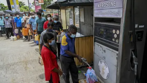 Getty Images People stand in a queue to buy kerosene oil used in cooking stoves in Colombo on August 31, 2021 following Sri Lanka's declaration of state of emergency over food shortages as private banks ran out of foreign exchange to finance imports.