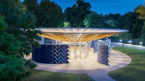 Iwan Baan Serpentine 2017 structure. It is of a round shape with blue panels around it. It is an open structure.