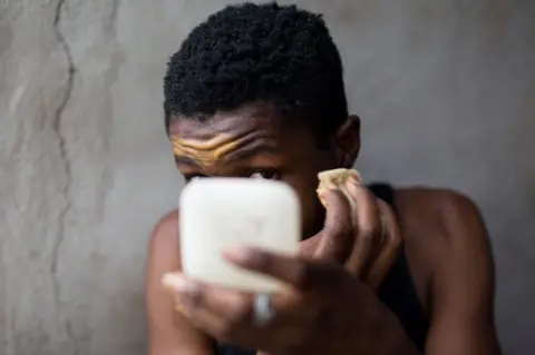 Lee Price Person applying makeup on their face