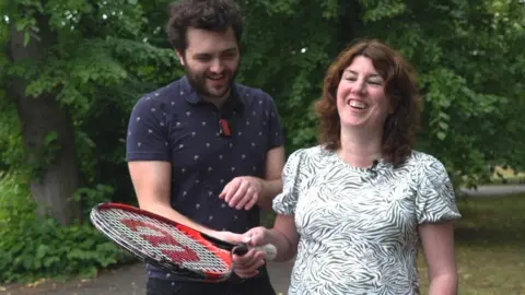 Reece shows Emma how to hit with the tennis racquet