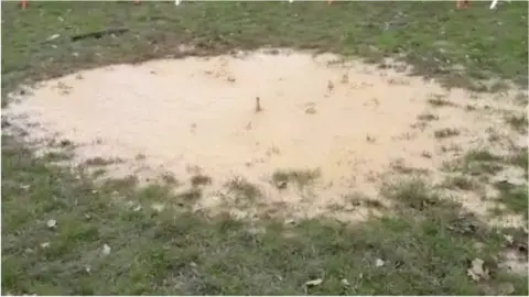 Puddles on a rugby pitch bubbling over