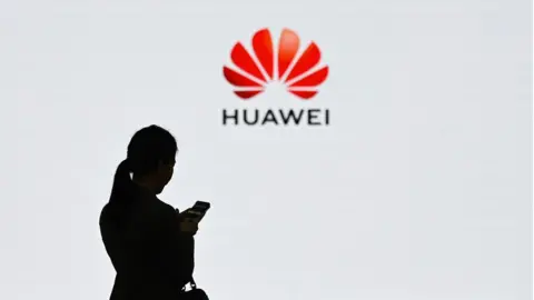 Getty Images A staff member of Huawei uses her mobile phone