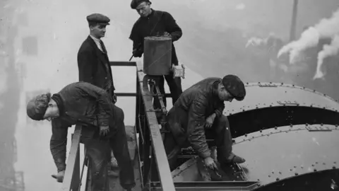 Getty Images Four men paint the top of Newport Bridge in 1935