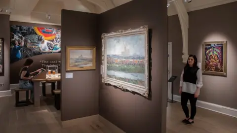 The House of Hues A woman looks at paintings in the gallery