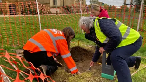 James Grant/BBC People taking part in an archaeology dig at Delapre Abbey