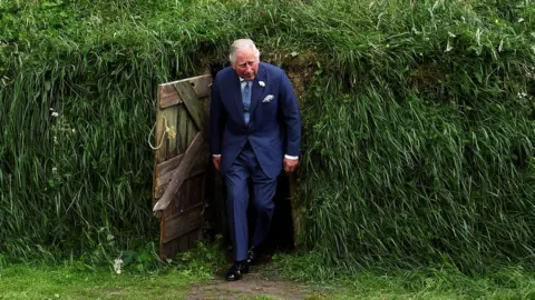 Reuters Prince Charles emerges from a recreation of a potato famine-era mud hut at University College Cork