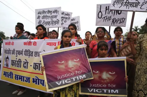 EPA People hold posters and candles during a march to protest against the rape of a seven-year-old girl in Mandsaur.