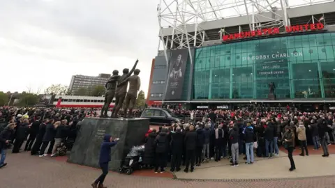 PA Media The funeral procession arrives outside Old Trafford in Manchester ahead of the funeral for the Manchester United and England great Sir Bobby Charlton