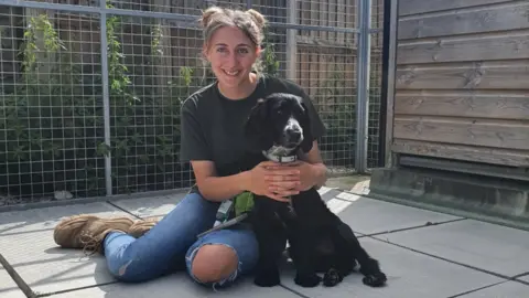 OAS Nala the black cocker spaniel with a member of staff at Oxfordshire Animal Sanctuary