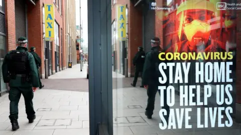 Stephen Davison/PSNI PSNI officer walking past a Covid-19 poster
