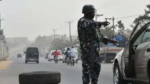 AFP via Getty Images A Nigerian policeman checks a car in Anambra state. File photo