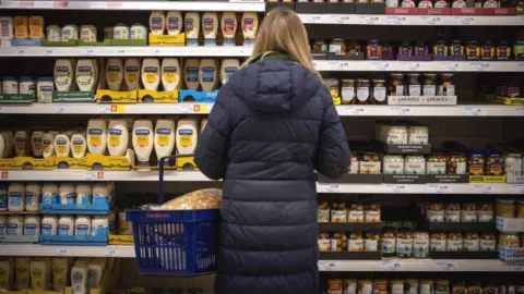 Getty Images Woman looking at supermarket shelves