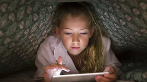 Getty Images Stock shot of child under covers with tablet computer
