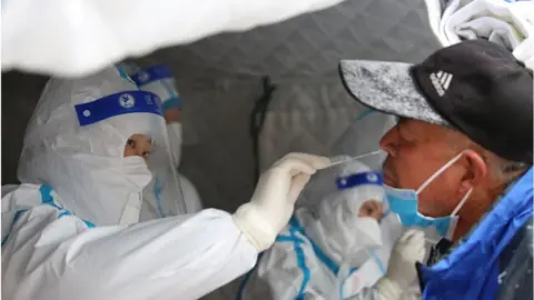 Getty Images Medical workers take swab samples on residents in a mass Covid-19 test in the snow in Shandan county in northwest China's Gansu province Saturday, Nov. 06, 2021.