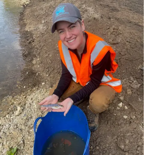 River Thame Conservation Trust Project Officer, Chels, moves a brown trout into the new fish pass