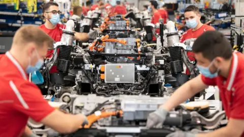 Getty Images Employees of German car manufacturer Porsche wear face masks as they work on power trains for the Taycan full-electric sportscar at the production site in Stuttgart, southern Germany, on May 12, 2020,