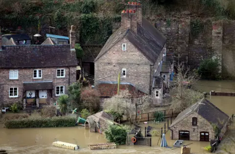 Nick Potts/PA Media The Vic Haddock boat house (right) under water on the River Severn