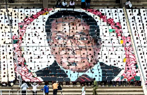 AFP School children hold an image of Zimbabwe's President Robert Mugabe during the country's 37th Independence Day celebrations at the National Sports Stadium in Harare April 18, 2017.