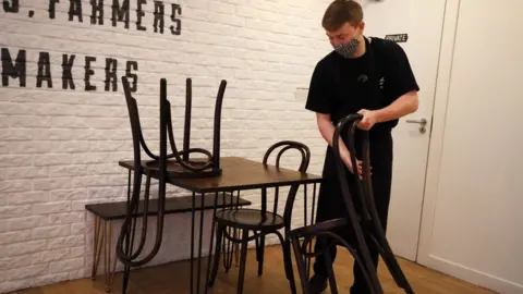 Pacemaker A cafe worker stacks chairs on top of a table