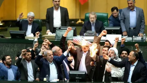 EPA Iranian MPs burn a US flag during a session at the parliament in Tehran, Iran (9 May 2018)